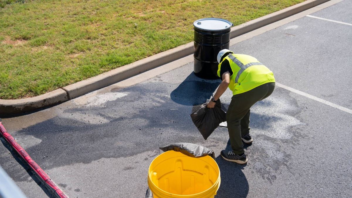Municipal crew member responding to a spill with absorbent socks and a containment drum